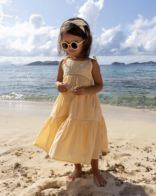 Early Sunday, Alice Dress in Vanilla, made from Cotton Dobby Swiss Dots fabric, featuring sleeveless with adjustable tie-up straps and a tiered silhouette, shown in a front view of model wearing it