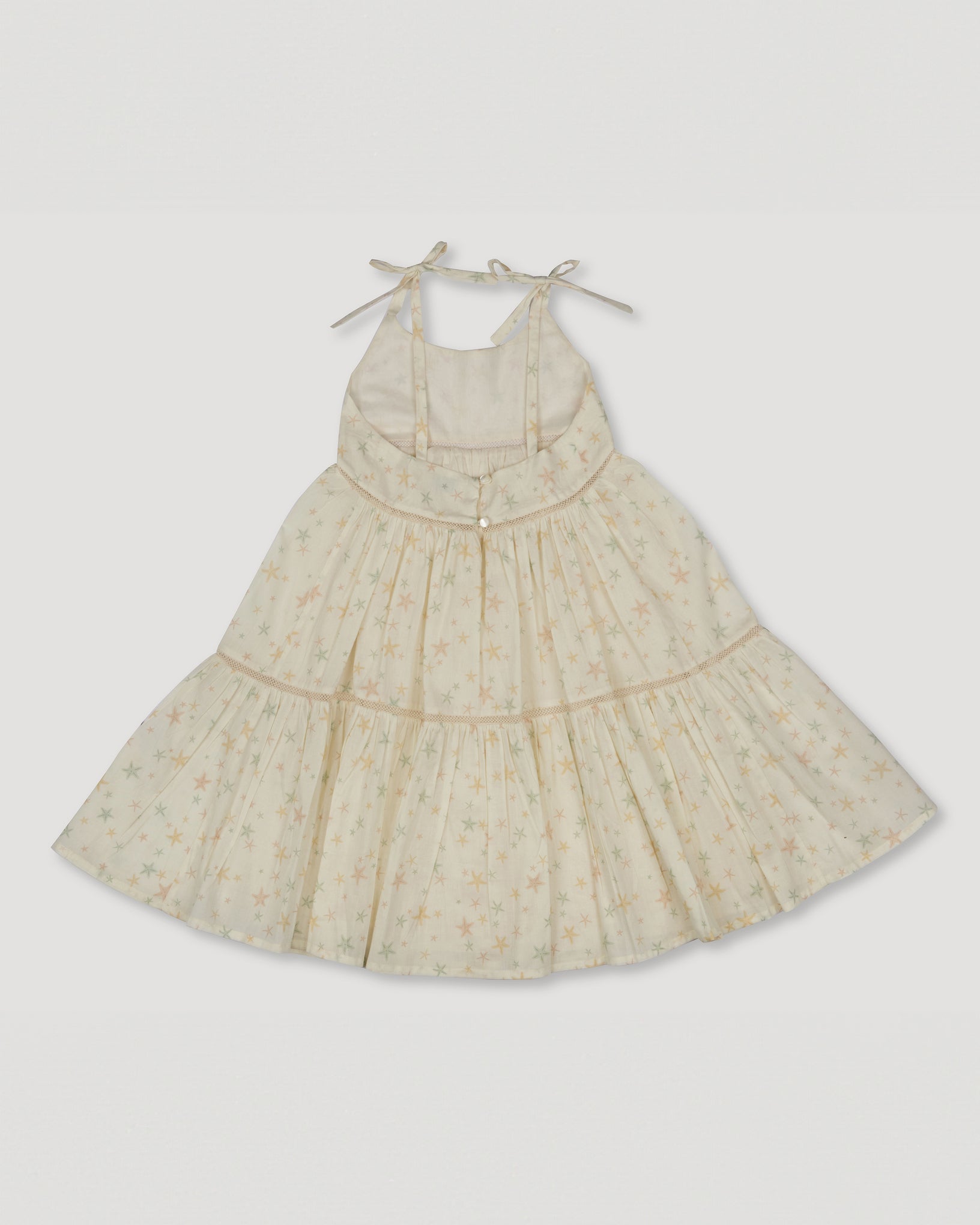 Early Sunday, Alice Dress in Star Fish print, made from Printed Cotton Cambric fabric, featuring sleeveless with adjustable tie-up straps and a tiered silhouette, shown in a back flat-lay view