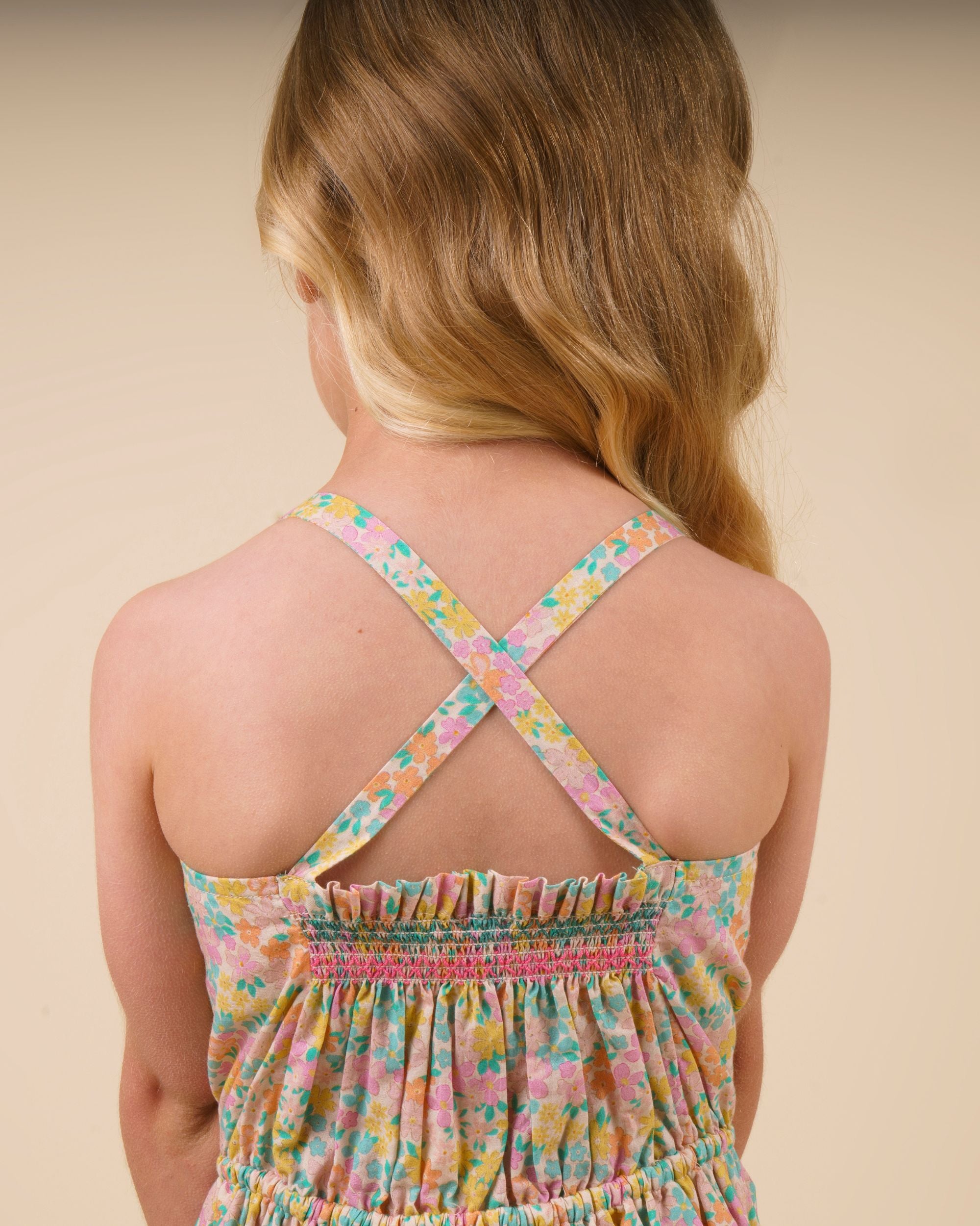 Early Sunday, Alisson Dress in Emma Floral Mint color, made from organic printed cotton cambric fabric, featuring smocked bodice, adjustable shoulder straps, sweet tassel accents, and a flowy gathered skirt, shown in a back view of model wearing.