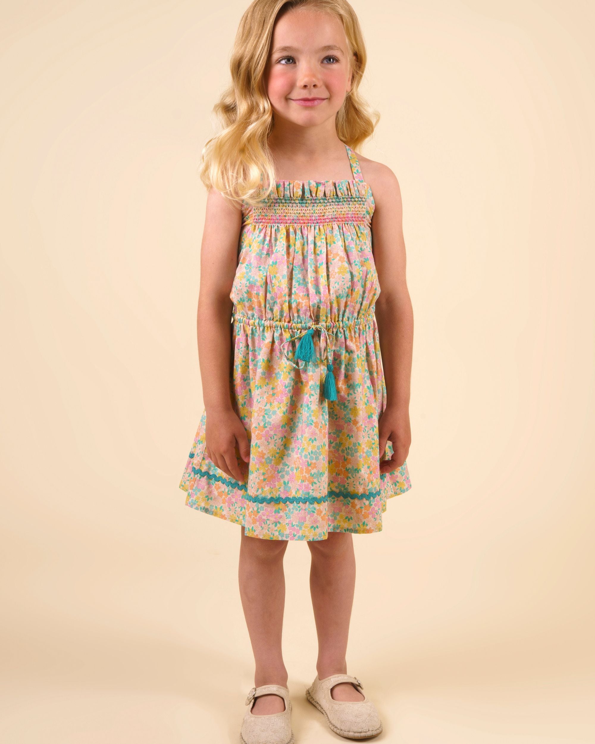 Early Sunday, Alisson Dress in Emma Floral Mint color, made from organic printed cotton cambric fabric, featuring smocked bodice, adjustable shoulder straps, sweet tassel accents, and a flowy gathered skirt, shown in a front view of model wearing.
