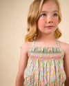 Early Sunday, Alisson Dress in Emma Floral Mint color, made from organic printed cotton cambric fabric, featuring smocked bodice, adjustable shoulder straps, sweet tassel accents, and a flowy gathered skirt, shown in a close up shot of model wearing it.