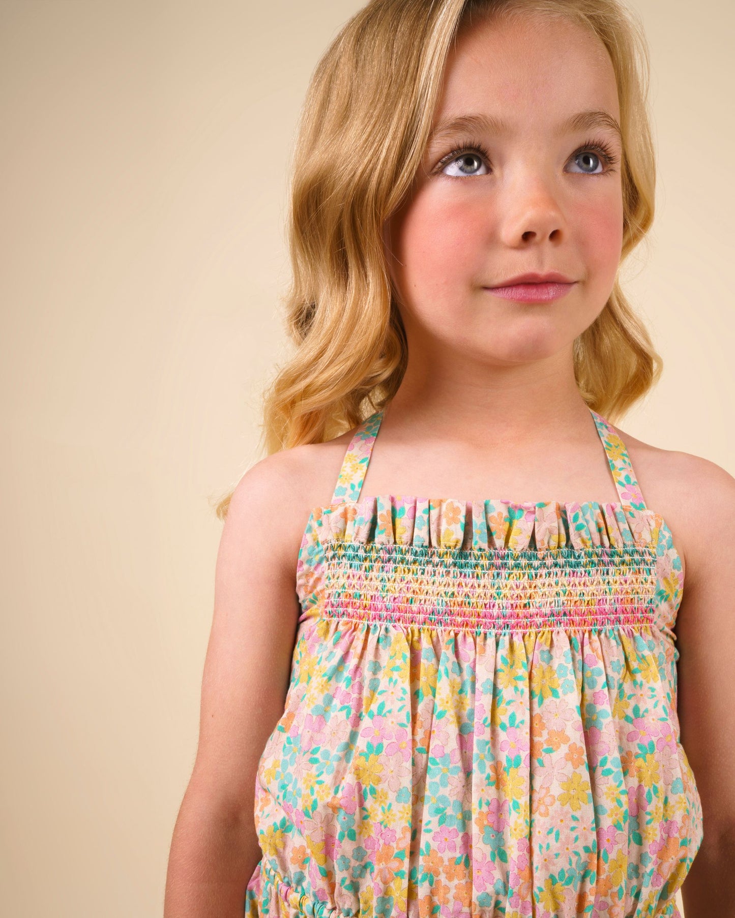 Early Sunday, Alisson Dress in Emma Floral Mint color, made from organic printed cotton cambric fabric, featuring smocked bodice, adjustable shoulder straps, sweet tassel accents, and a flowy gathered skirt, shown in a close up shot of model wearing it.