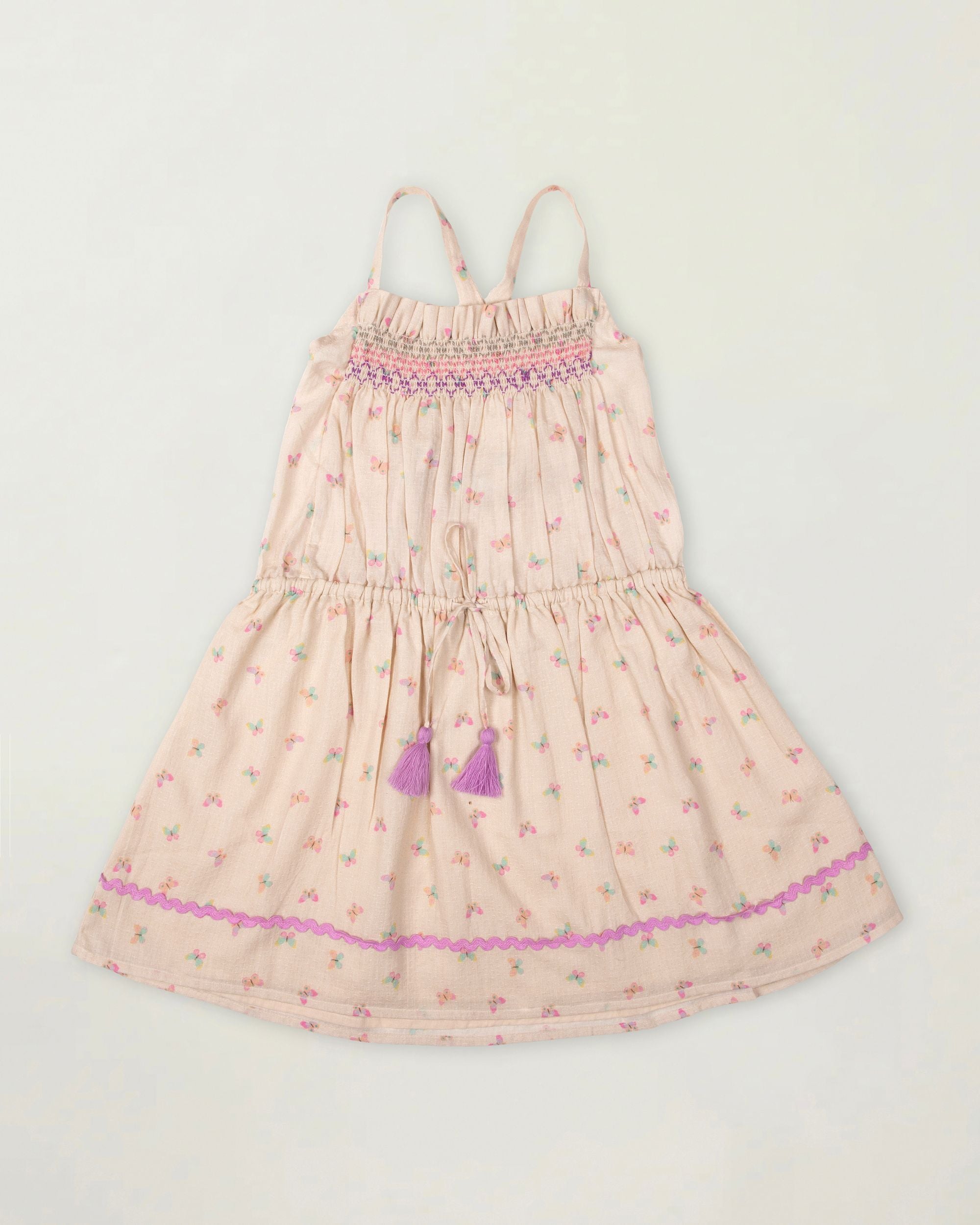 Early Sunday, Alisson Dress in butterfly print color, made from printed cotton tiny swiss dobby fabric, featuring smocked bodice, adjustable shoulder straps, sweet tassel accents, and a flowy gathered skirt, shown in a front flat-lay view.