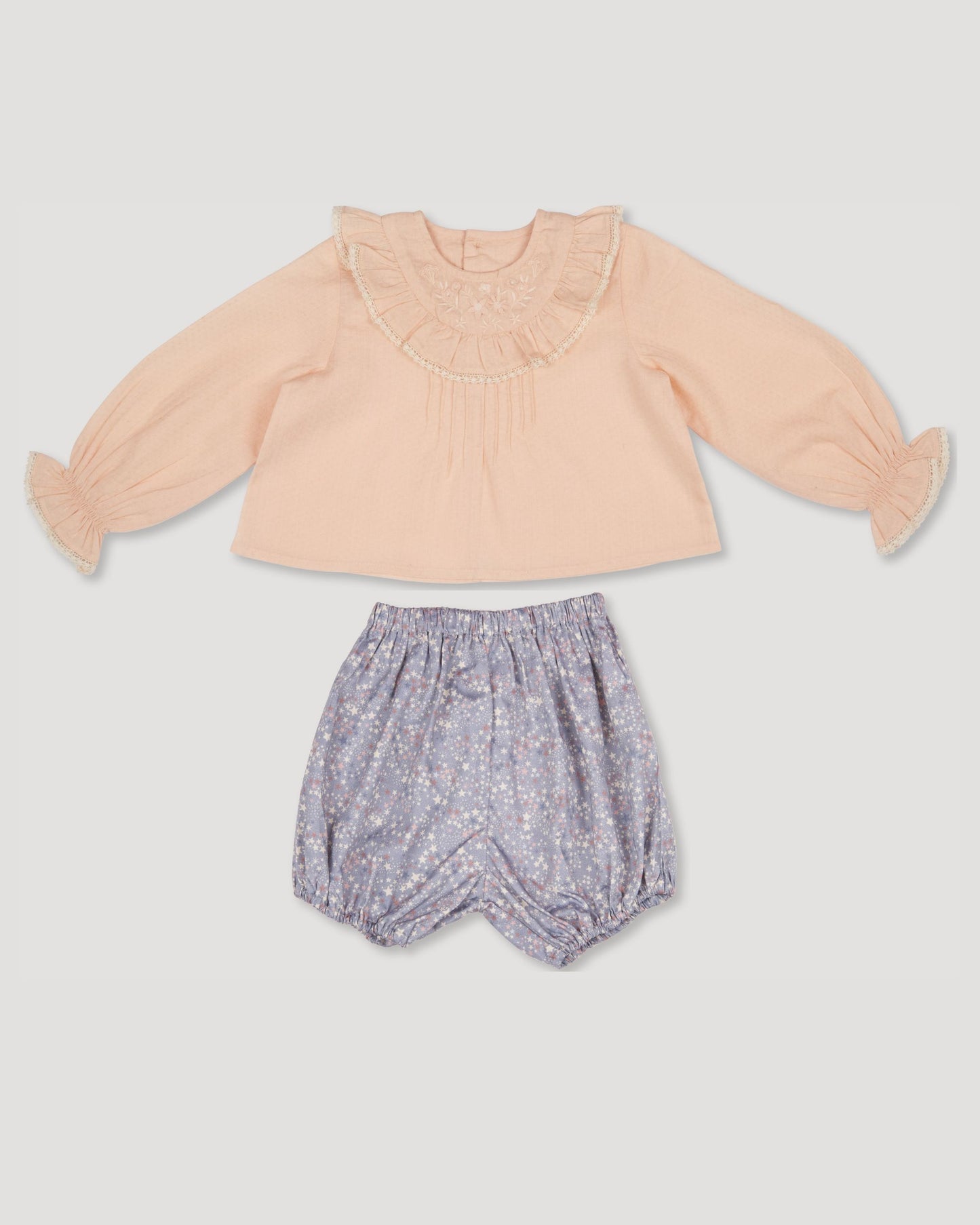 Early Sunday, Amy Baby Blouse & Bloomer Set in Nude & Celestial print, made from Dyed Cotton Swiss Dobby Tiny Dots fabric, featuring a delicate embroidery & lace-trimmed ruffles with elasticated bloomers, shown in a front flat-lay view