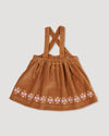 Early Sunday, Anni Skirt in Almond, made from Dyed Cotton Velvet fabric, featuring Delicate floral embroidery along the hem with playful cross-back straps, shown in a back flat-lay view