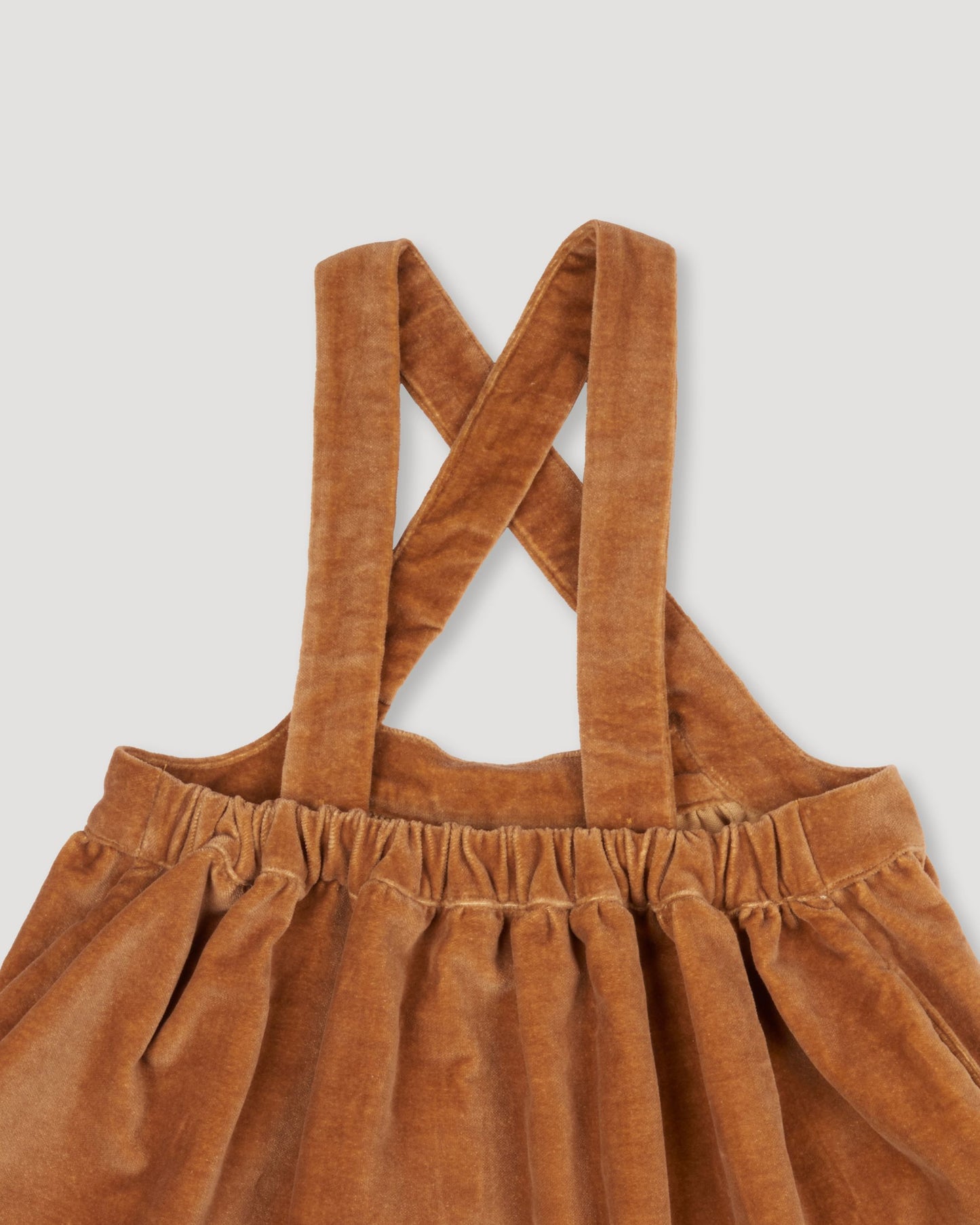 Early Sunday, Anni Skirt in Almond, made from Dyed Cotton Velvet fabric, featuring Delicate floral embroidery along the hem with playful cross-back straps, shown in a closeup flat-lay view