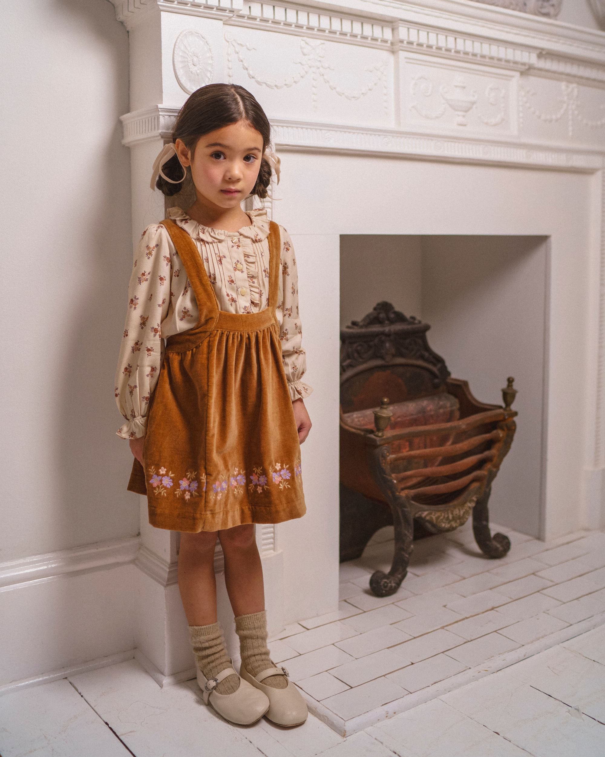 Early Sunday, Anni Skirt in Almond, made from Dyed Cotton Velvet fabric, featuring Delicate floral embroidery along the hem with playful cross-back straps, shown in a front view of model wearing it