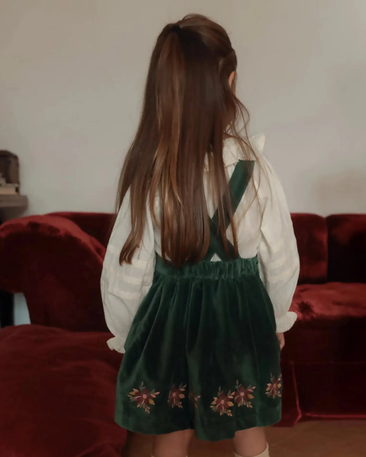 Early Sunday, Annie Skirt in Forest Green, made from Cotton Velvet Velour's fabric, featuring an A-line silhouette with adjustable cross-back straps and soft gathers, shown in a back view of model wearing it