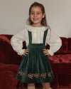 Early Sunday, Annie Skirt in Forest Green, made from Cotton Velvet Velour's fabric, featuring an A-line silhouette with adjustable cross-back straps and soft gathers, shown in a front view of model wearing it