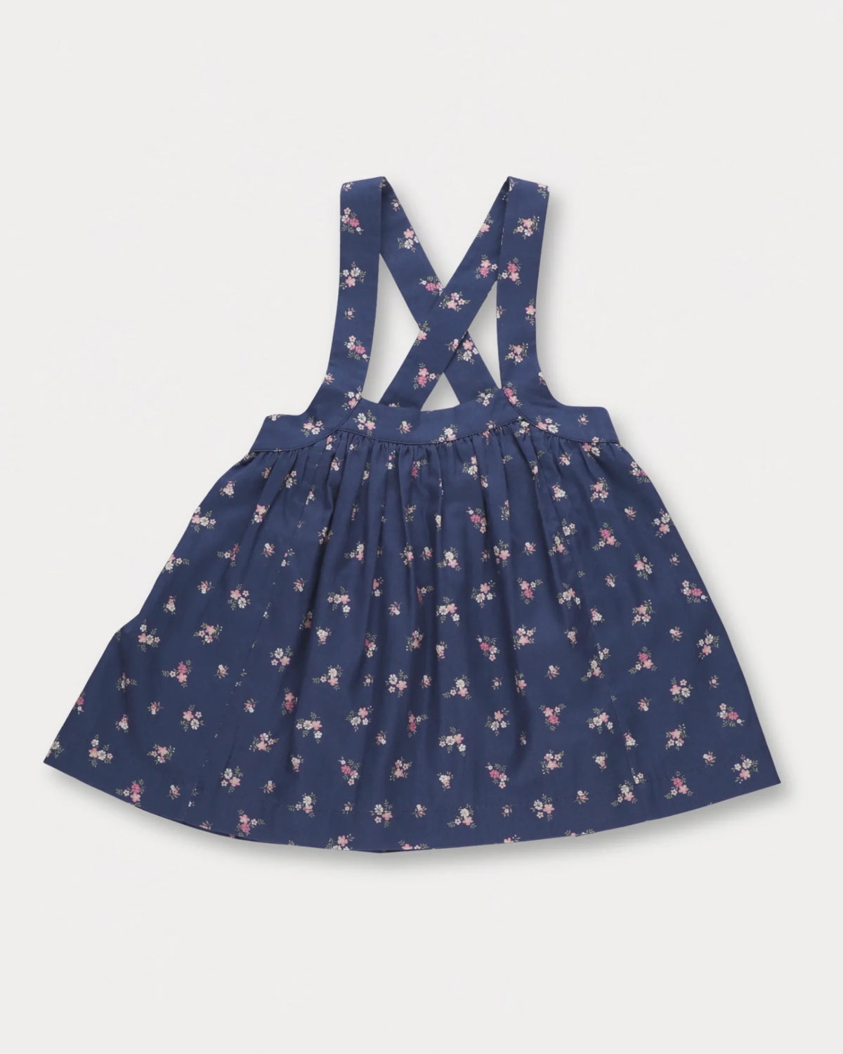Early Sunday, Annie Skirt in Ditsy Bouquet Navy, made from Printed Cotton Satin fabric, featuring an A-line silhouette with adjustable cross-back straps and soft gathers, shown in a front flat-lay view