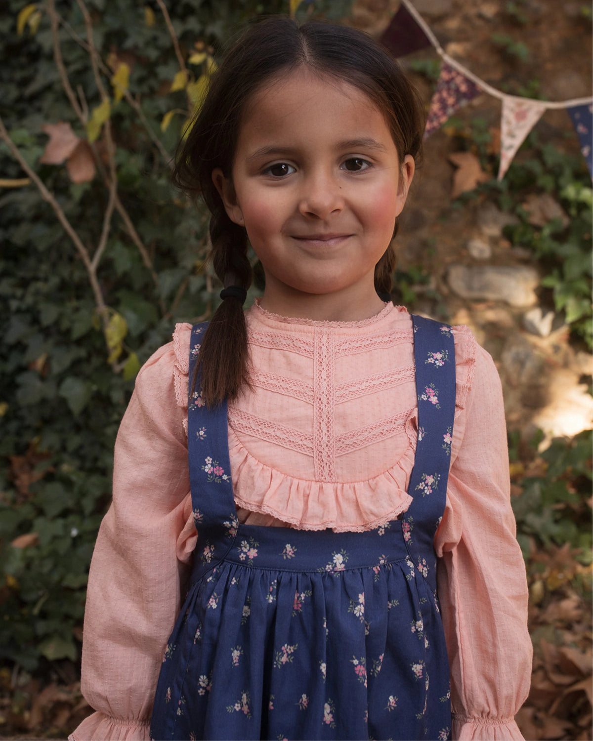 Early Sunday, Annie Skirt in Ditsy Bouquet Navy, made from Printed Cotton Satin fabric, featuring an A-line silhouette with adjustable cross-back straps and soft gathers, shown in a close up shot of model wearing it