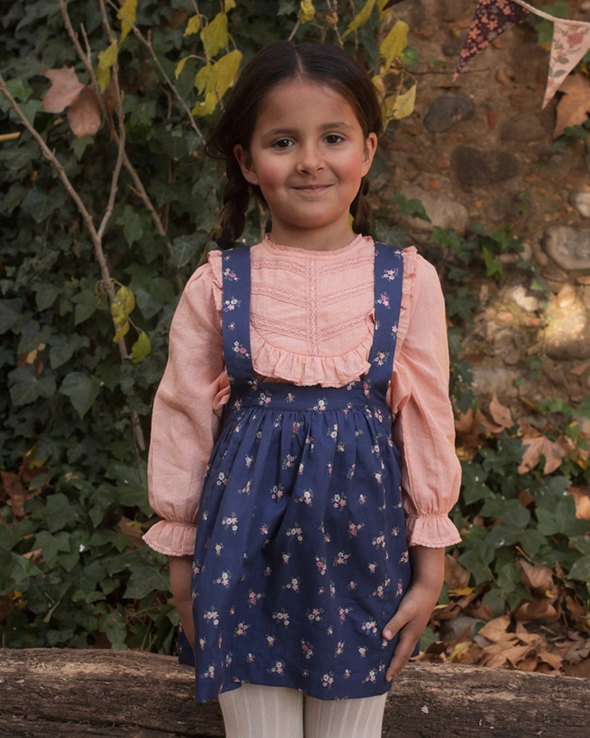 Early Sunday, Annie Skirt in Ditsy Bouquet Navy, made from Printed Cotton Satin fabric, featuring an A-line silhouette with adjustable cross-back straps and soft gathers, shown in a front view of model wearing it
