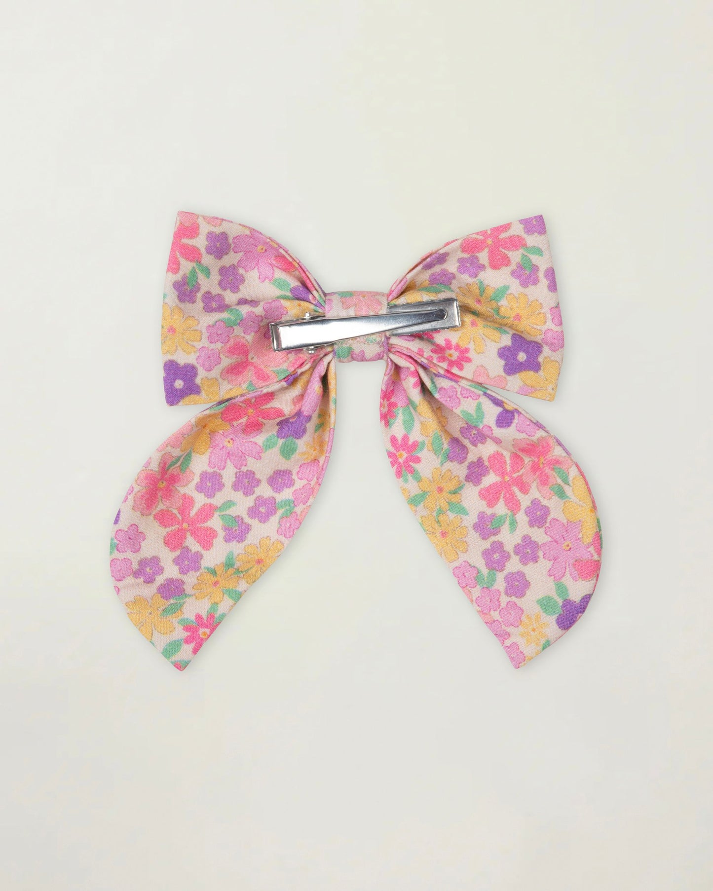 Early Sunday, Audrey Clip in Emma Floral Purple color, made from Organic Printed Cotton Cambric fabric, featuring a fabric bow design with a secure hair clip fastening, shown in a back flat-lay view