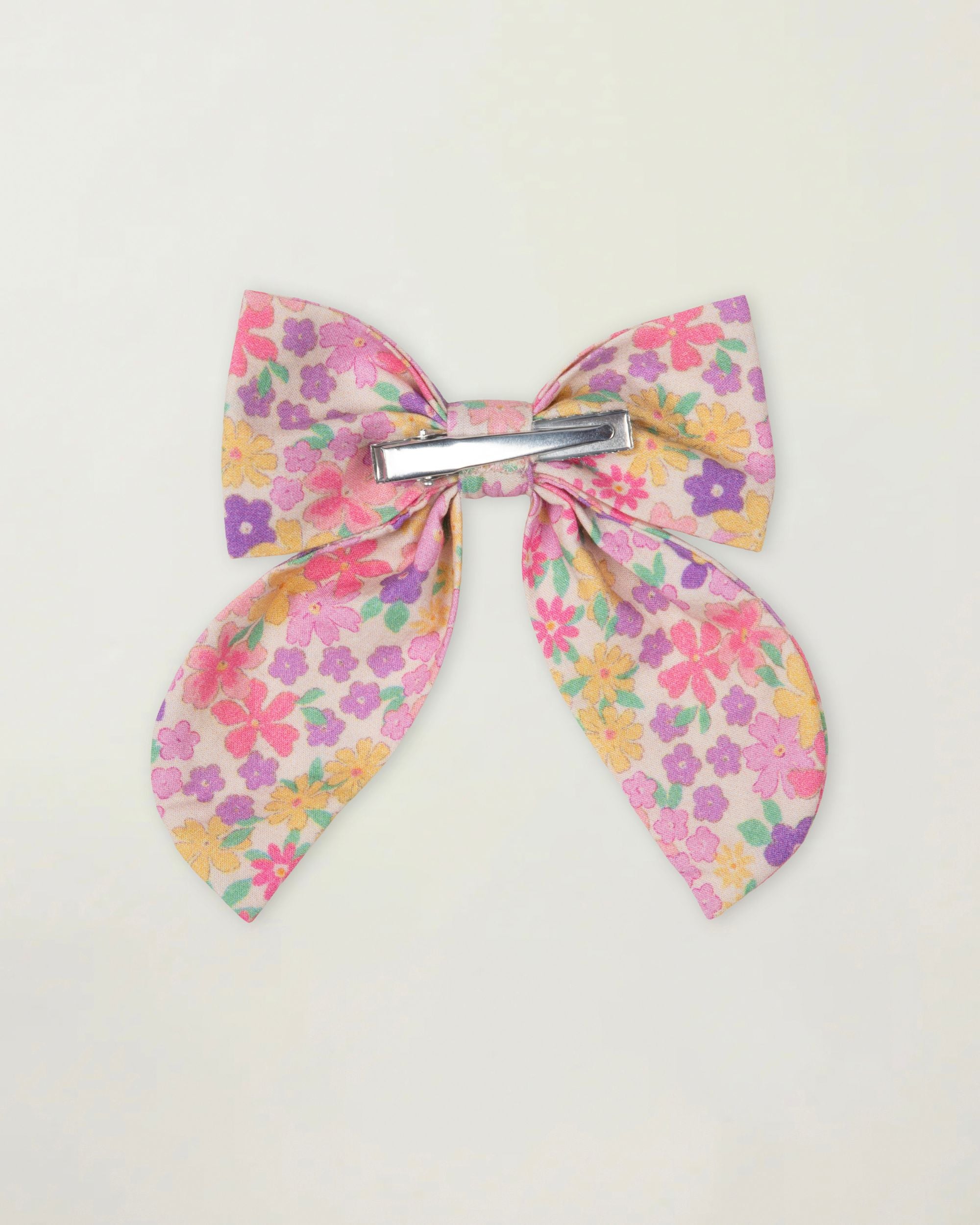 Early Sunday, Audrey Clip in Emma Floral Purple color, made from Organic Printed Cotton Cambric fabric, featuring a fabric bow design with a secure hair clip fastening, shown in a back flat-lay view