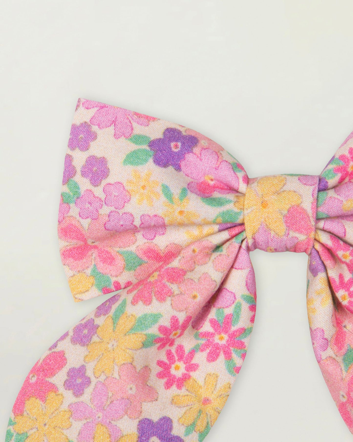 Early Sunday, Audrey Clip in Emma Floral Purple color, made from Organic Printed Cotton Cambric fabric, featuring a fabric bow design with a secure hair clip fastening, shown in a closeup flat-lay view