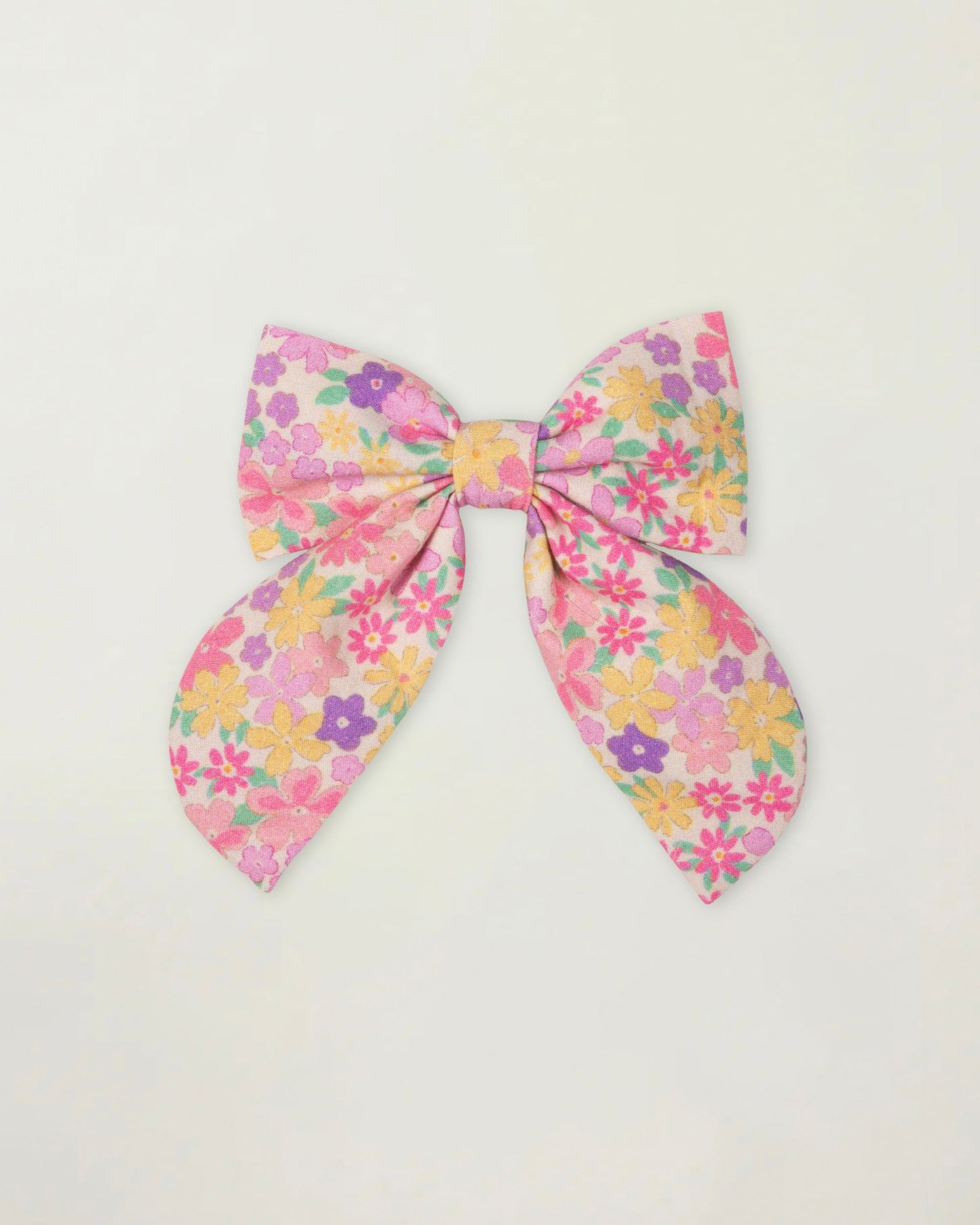Early Sunday, Audrey Clip in Emma Floral Purple color, made from Organic Printed Cotton Cambric fabric, featuring a fabric bow design with a secure hair clip fastening, shown in a front flat-lay view