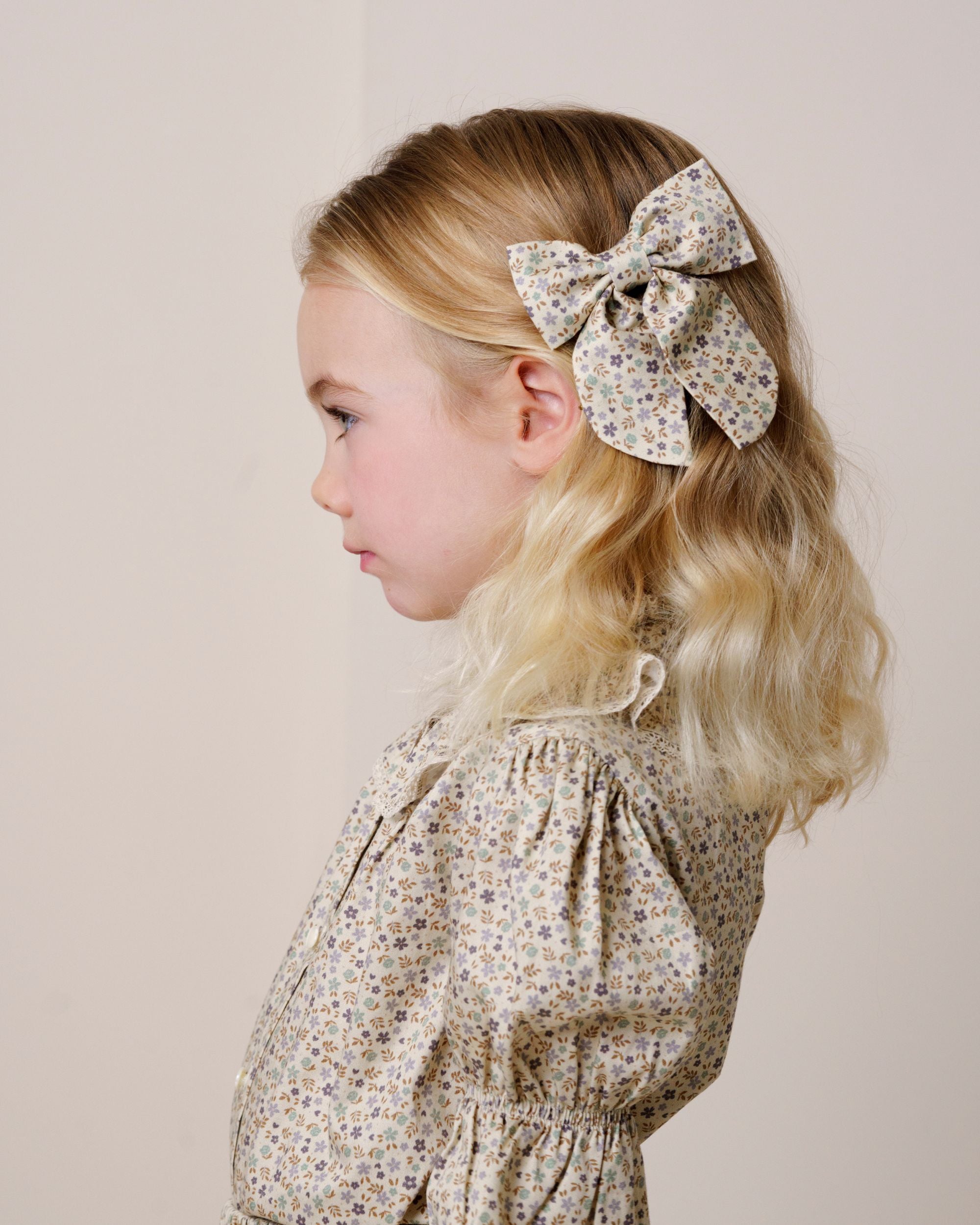Early Sunday, Audrey Clip in Mini Flowers print, made from Printed 60s Cotton Satin fabric, featuring a fabric bow design with a secure hair clip fastening, shown in a close up shot of model wearing it