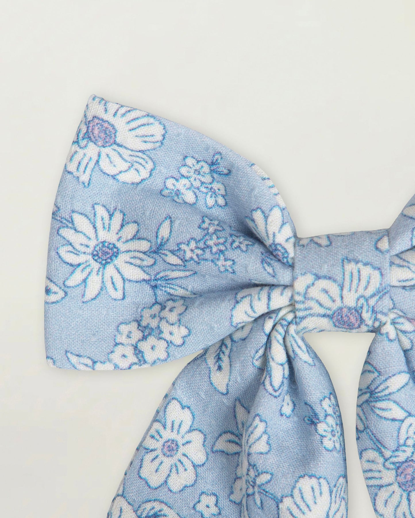 Early Sunday, Audrey Clip in Tonal Floral Blue color, made from Printed 70% Cotton, 30% Linen fabric, featuring a fabric bow design with a secure hair clip fastening, shown in a closeup flat-lay view