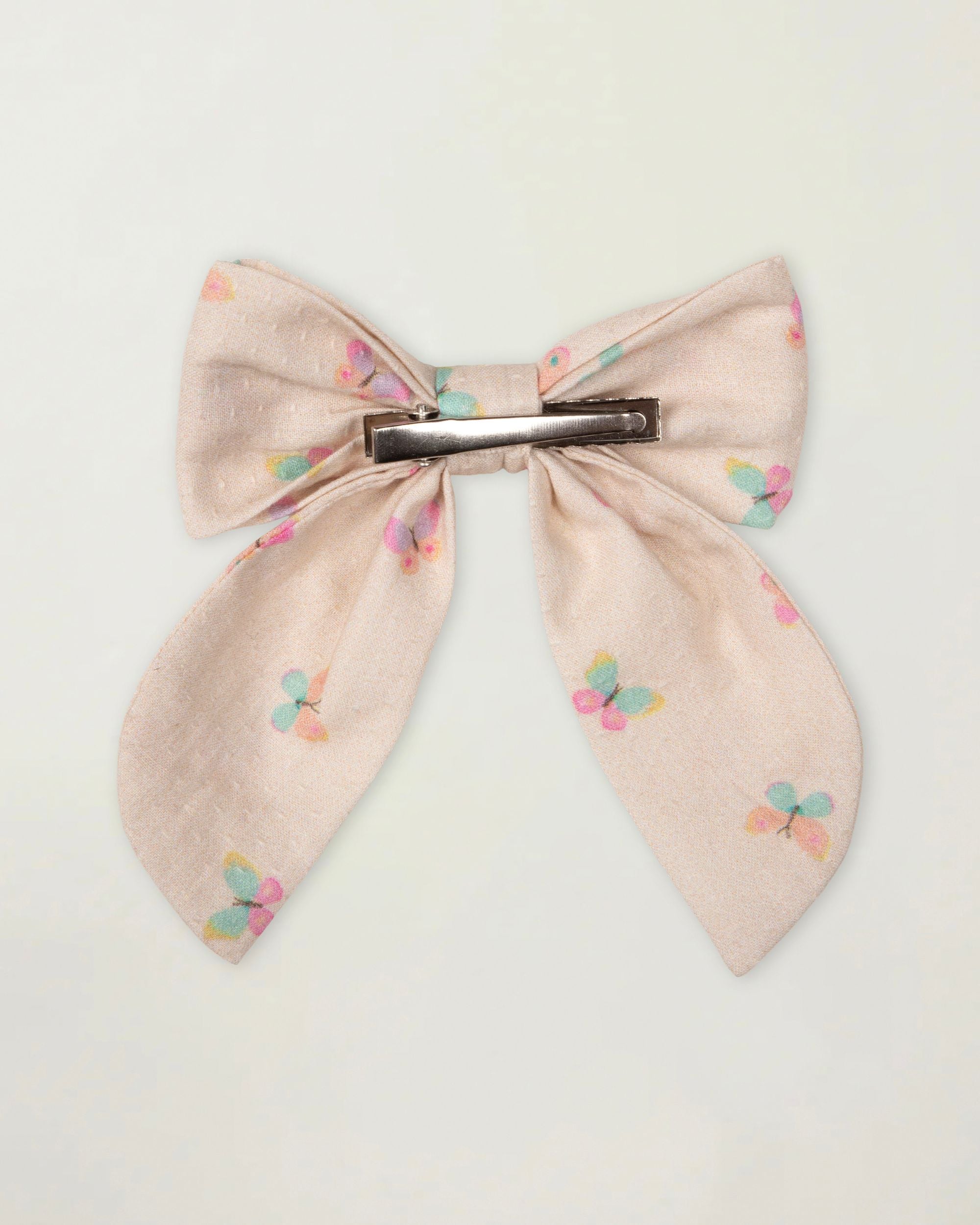 Early Sunday, Audrey Clip in Butterflies print, made from Printed Cotton Tiny Swiss Dobby fabric, featuring a fabric bow design with a secure hair clip fastening, shown in a back flat-lay view
