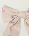 Early Sunday, Audrey Clip in Butterflies print, made from Printed Cotton Tiny Swiss Dobby fabric, featuring a fabric bow design with a secure hair clip fastening, shown in a closeup flat-lay view