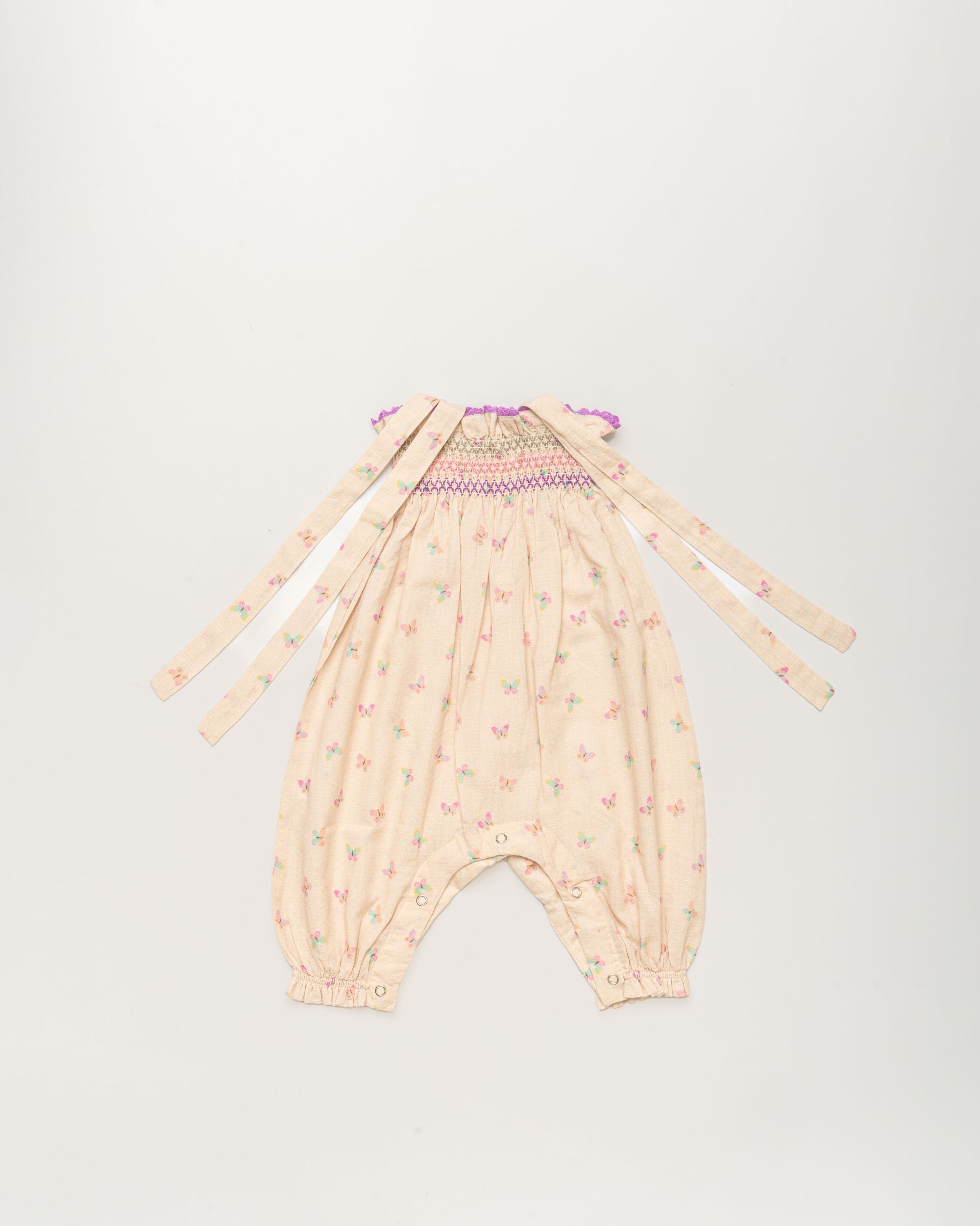 Early Sunday, Audrey Overall Baby Romper in Butterflies print, made from 100% Cotton Swiss Dobby Tiny Dots fabric, featuring tie-up shoulder straps with dot texture & smocked waistband, shown in a back flat-lay view