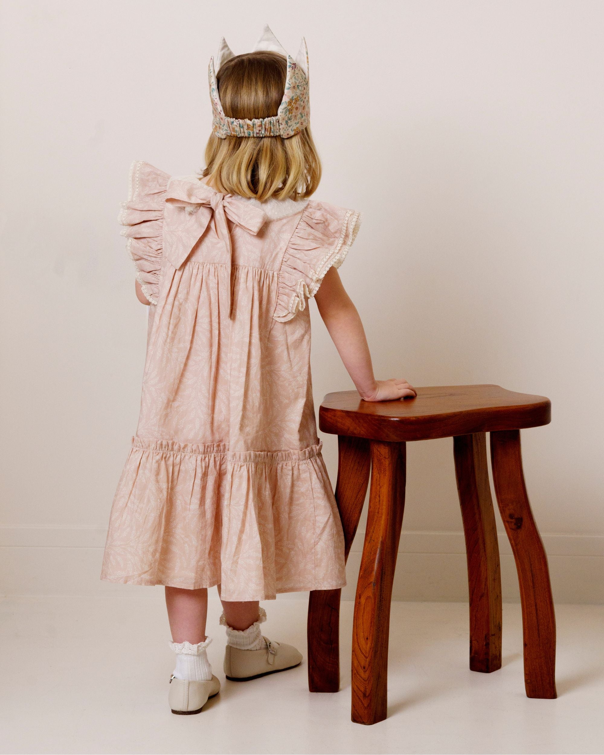 Early Sunday, Aurelia Dress in Feather print, made from Printed Cotton Cambric fabric, featuring Layered ruffles with flutter sleeves, shown in a back view of model wearing