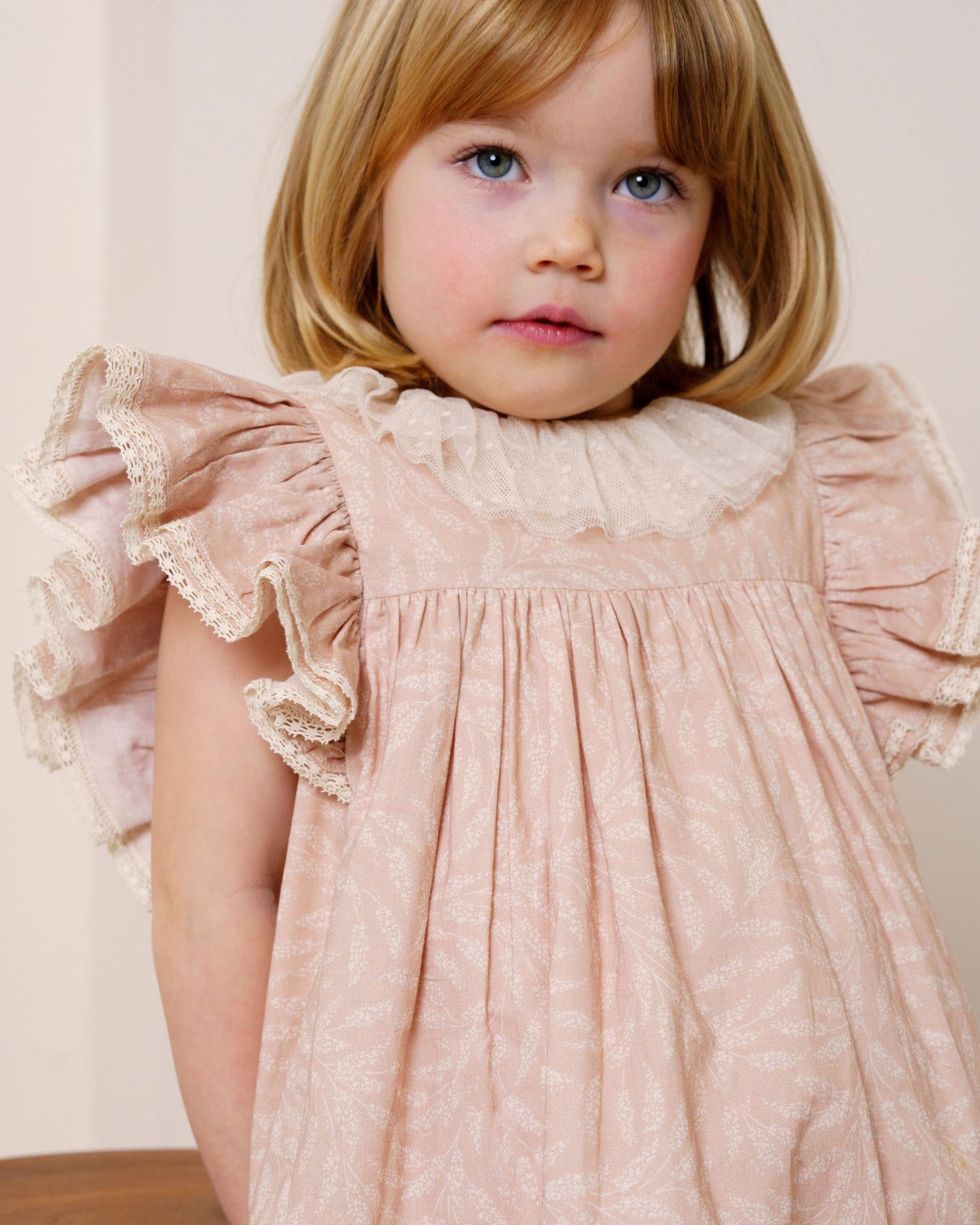 Early Sunday, Aurelia Dress in Feather print, made from Printed Cotton Cambric fabric, featuring Layered ruffles with flutter sleeves, shown in a close up shot of model wearing it