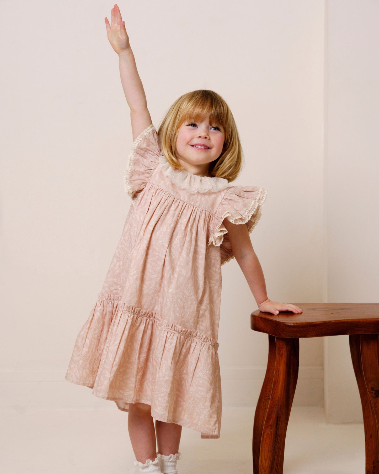 Early Sunday, Aurelia Dress in Feather print, made from Printed Cotton Cambric fabric, featuring Layered ruffles with flutter sleeves, shown in a front view of model wearing it