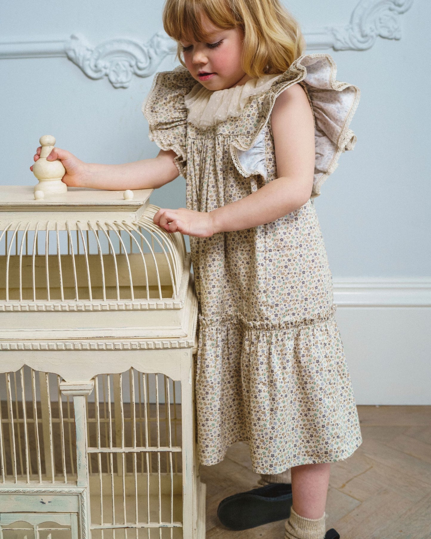 Early Sunday, Aurelia Dress in Miny Flowers print, made from Printed Cotton Satin fabric, featuring Layered ruffles with flutter sleeves, shown in a front view of a model wearing it in a studio setting