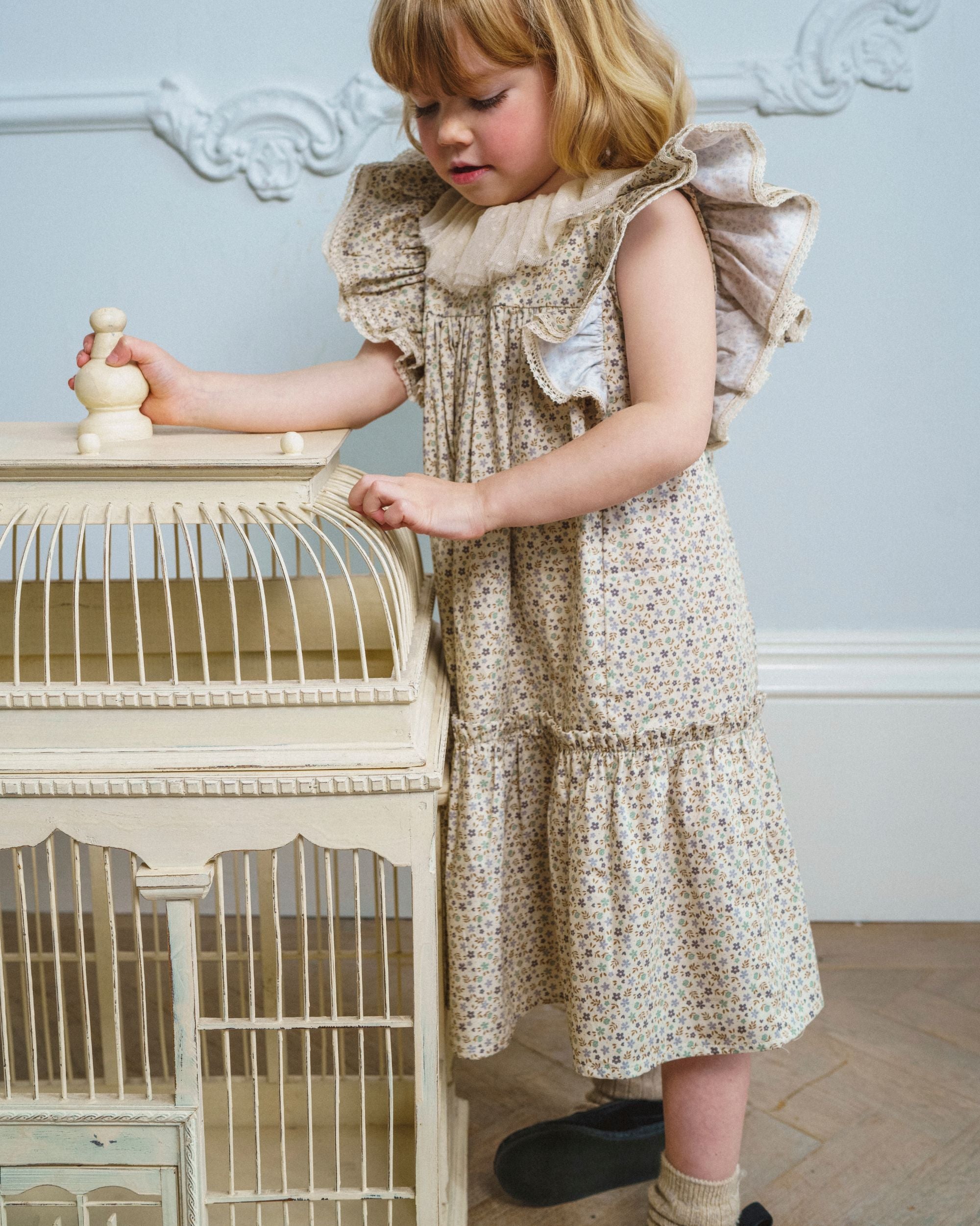 Early Sunday, Aurelia Dress in Miny Flowers print, made from Printed Cotton Satin fabric, featuring Layered ruffles with flutter sleeves, shown in a front view of a model wearing it in a studio setting