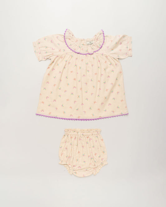 Early Sunday, Baby Bella Dress with Bloomer in Butterflies print, made from 100% Cotton Swiss Dobby Tiny Dots fabric, featuring short puff sleeves with a lilac lace & matching bloomers, shown in a front flat-lay view