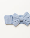 Early Sunday, Baby's Bow Headband in Summer Sky color, made from Chambray fabric, featuring a wide bow design, shown in a closeup flat-lay view