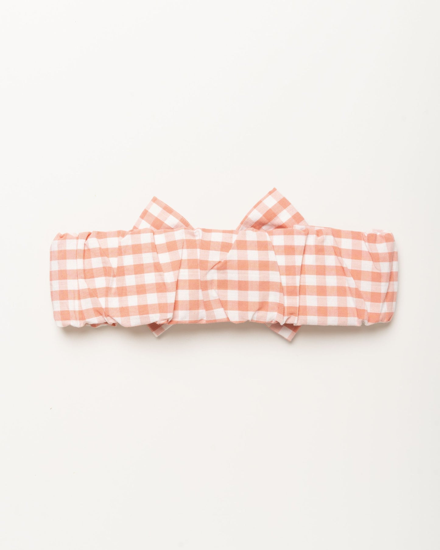 Early Sunday, Baby's Bow Headband in Peony color, made from Gingham Check fabric, featuring a wide bow design, shown in a back flat-lay view