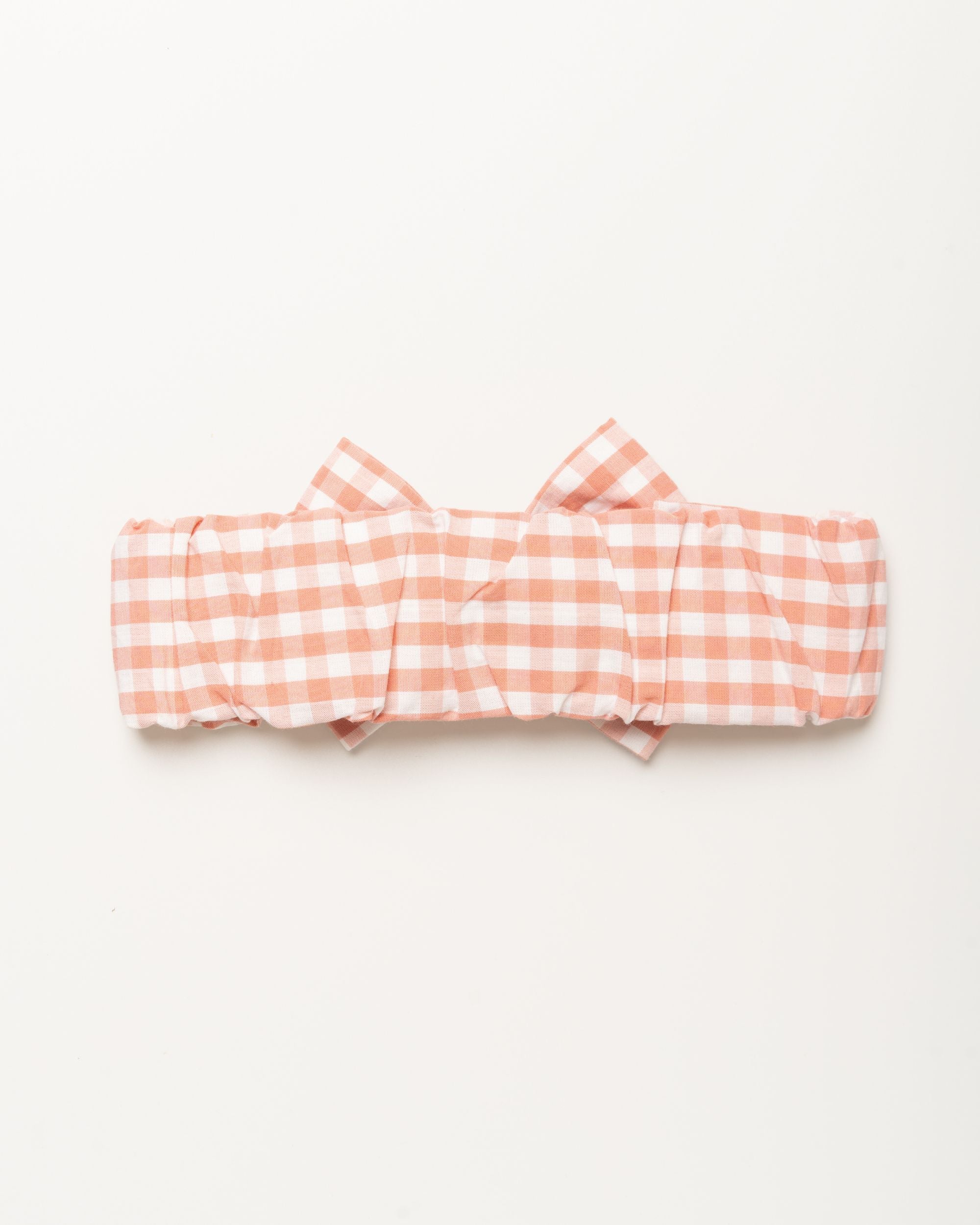 Early Sunday, Baby's Bow Headband in Peony color, made from Gingham Check fabric, featuring a wide bow design, shown in a back flat-lay view