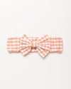 Early Sunday, Baby's Bow Headband in Peony color, made from Gingham Check fabric, featuring a wide bow design, shown in a front flat-lay view