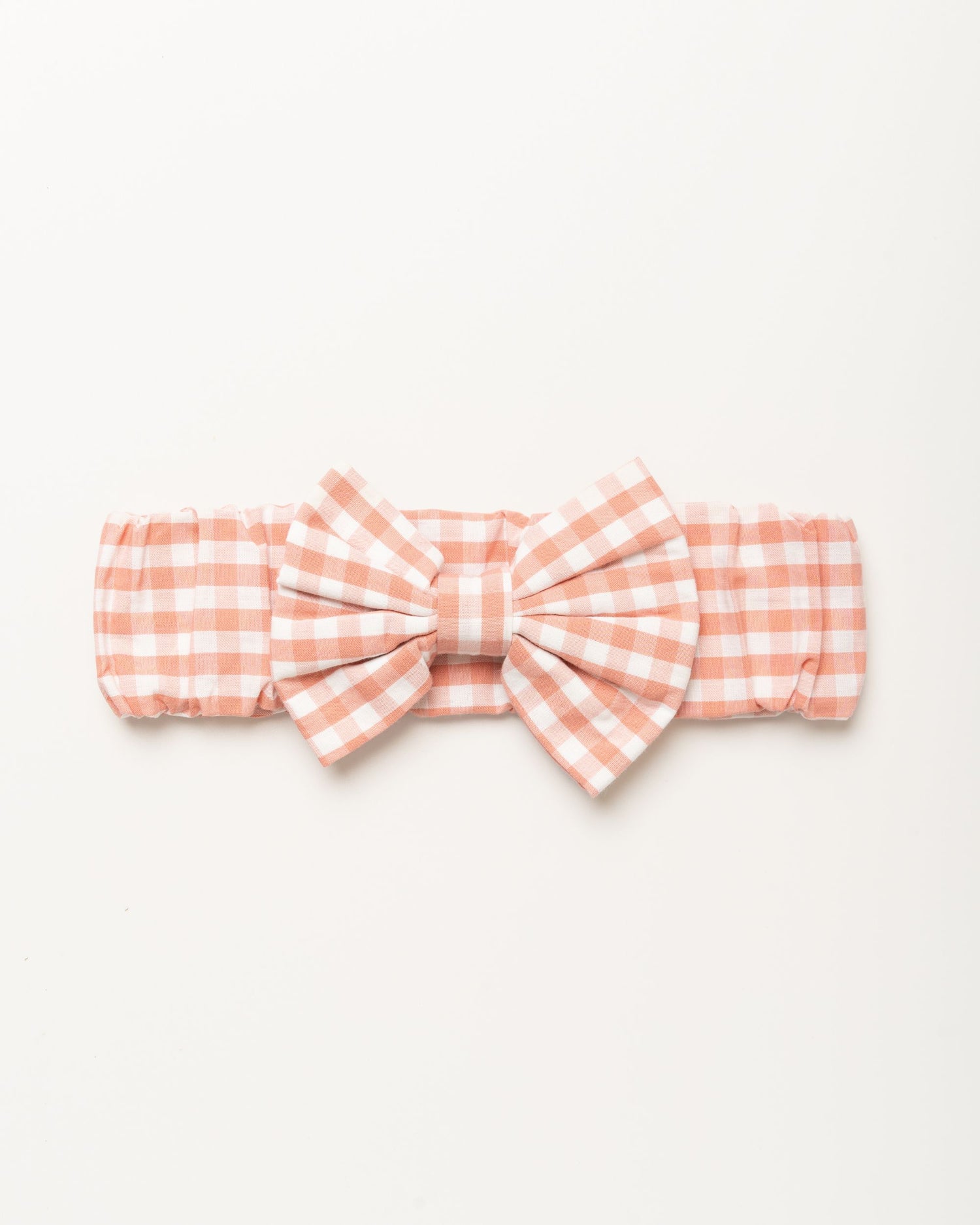 Early Sunday, Baby's Bow Headband in Peony color, made from Gingham Check fabric, featuring a wide bow design, shown in a front flat-lay view