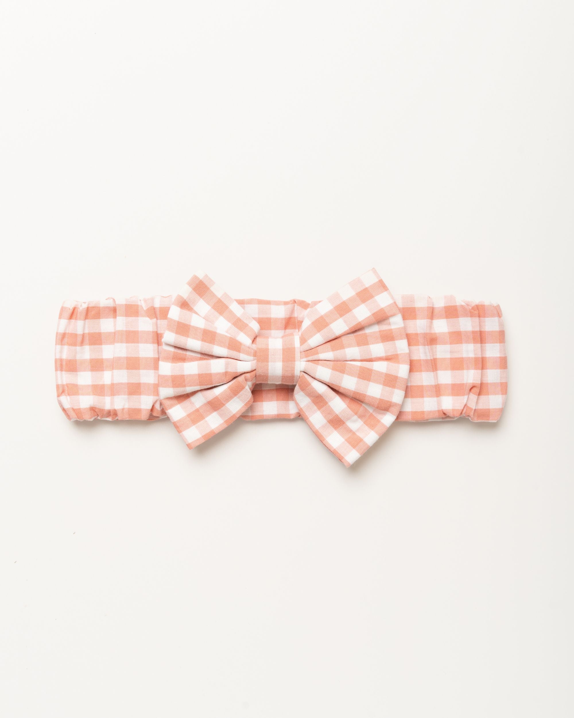 Early Sunday, Baby's Bow Headband in Peony color, made from Gingham Check fabric, featuring a wide bow design, shown in a front flat-lay view