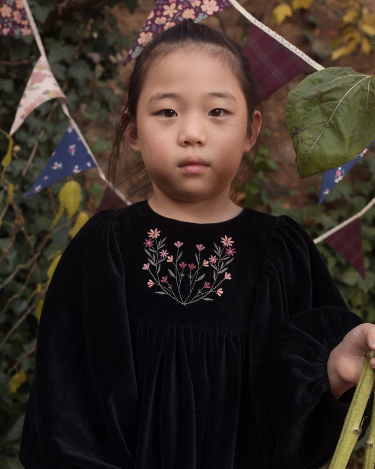 Early Sunday, Belle Dress in Black, made from Cotton Velvet Velour's fabric, featuring a flowing silhouette with puff sleeves and gentle gathers, shown in a close up shot of model wearing outdoors