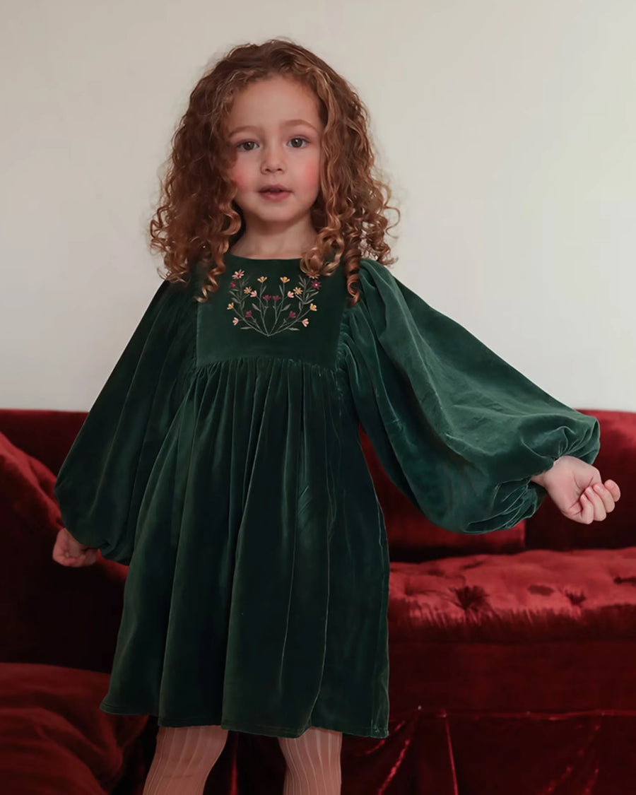 Early Sunday, Belle Dress in Forest Green, made from Cotton Velvet Velour's fabric, featuring a flowing silhouette with puff sleeves and gentle gathers, shown in a front view of model wearing it