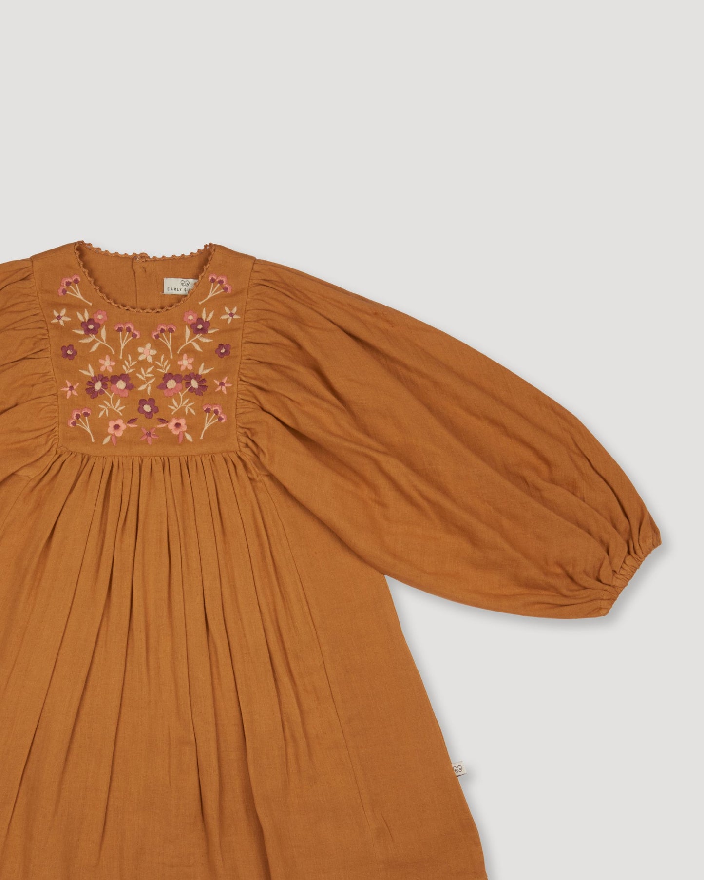 Early Sunday, Belle Dress in Almond, made from Dyed Cotton Double Gauze fabric, featuring Hand-embroidered floral bodice with voluminous puff sleeves for a soft, enchanting silhouette, shown in a closeup flat-lay view