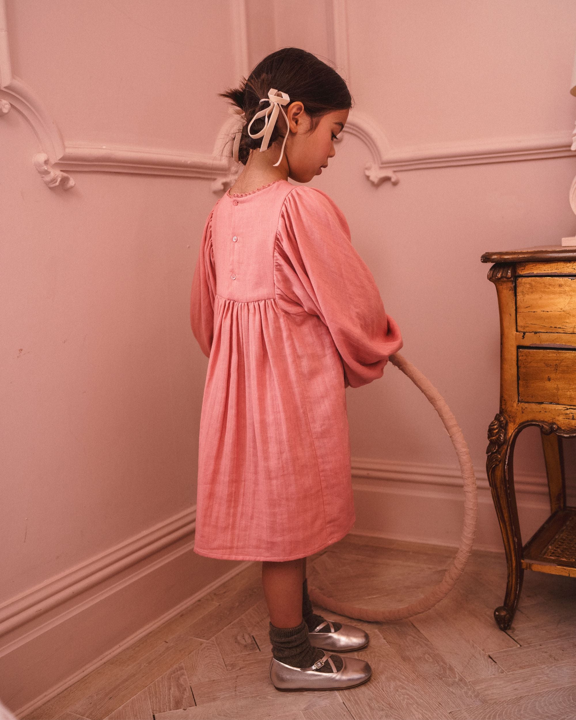 Early Sunday, Belle Dress in Rose, made from Dyed Cotton Double Gauze fabric, featuring Hand-embroidered floral bodice with voluminous puff sleeves for a soft, enchanting silhouette, shown in a side view of model wearing it