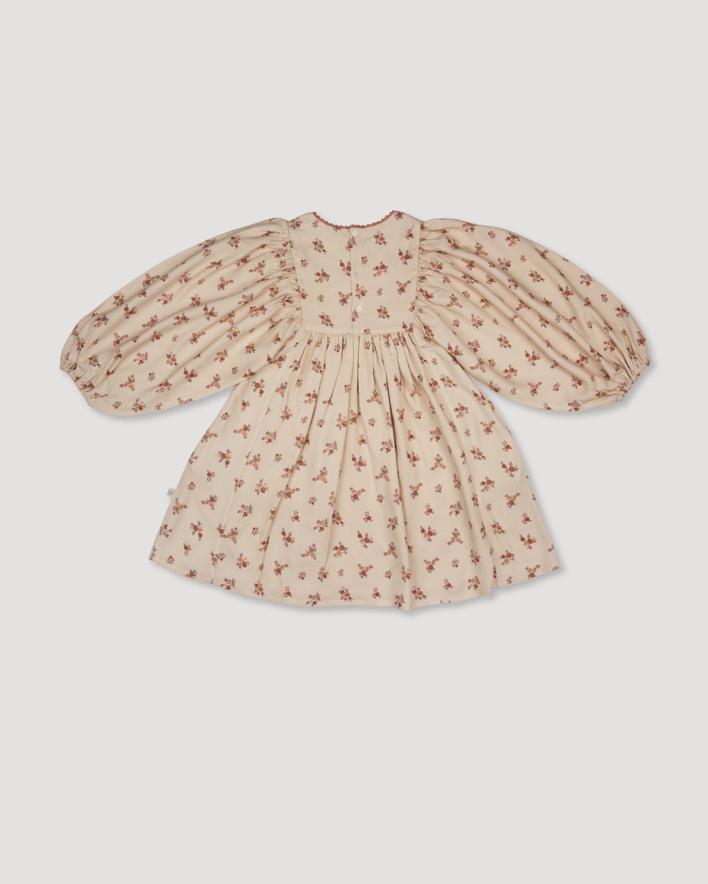 Early Sunday, Belle Dress in Ditsy Bouquet Cream print, made from Printed Viscose Rayon Twill fabric, featuring Hand-embroidered floral bodice with voluminous puff sleeves for a soft, enchanting silhouette, shown in a back flat-lay view