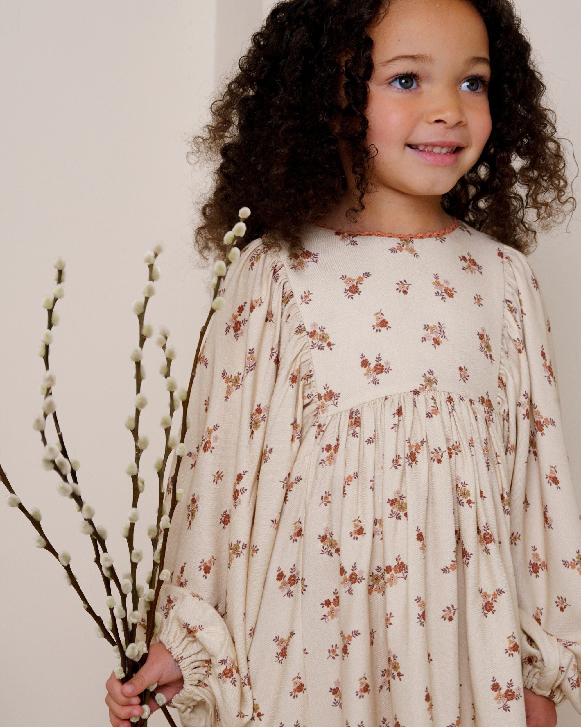 Early Sunday, Belle Dress in Ditsy Bouquet Cream print, made from Printed Viscose Rayon Twill fabric, featuring Hand-embroidered floral bodice with voluminous puff sleeves for a soft, enchanting silhouette, shown in a close up shot of model wearing it