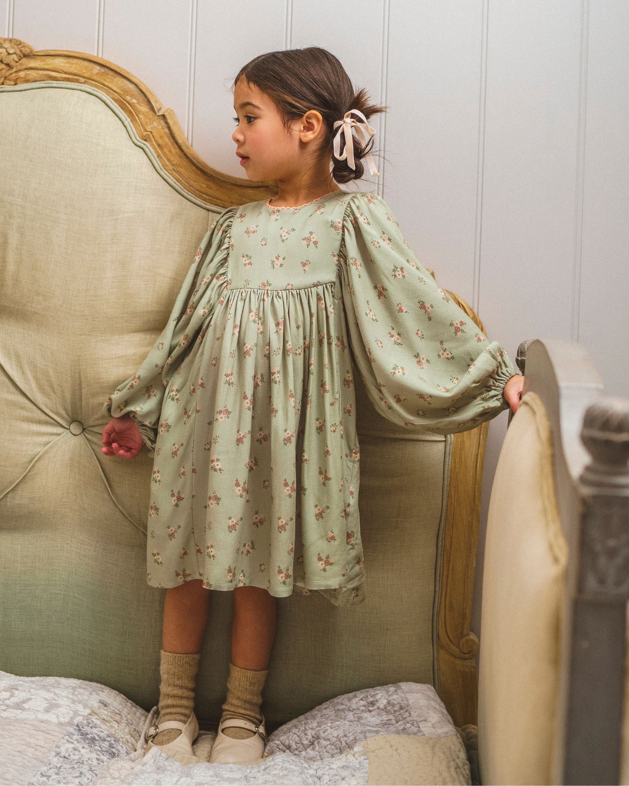 Early Sunday, Belle Dress in Ditsy Bouquet Jade print, made from Printed Viscose Rayon Twill fabric, featuring Hand-embroidered floral bodice with voluminous puff sleeves for a soft, enchanting silhouette, shown in a front view of a models wearing it in a studio setting