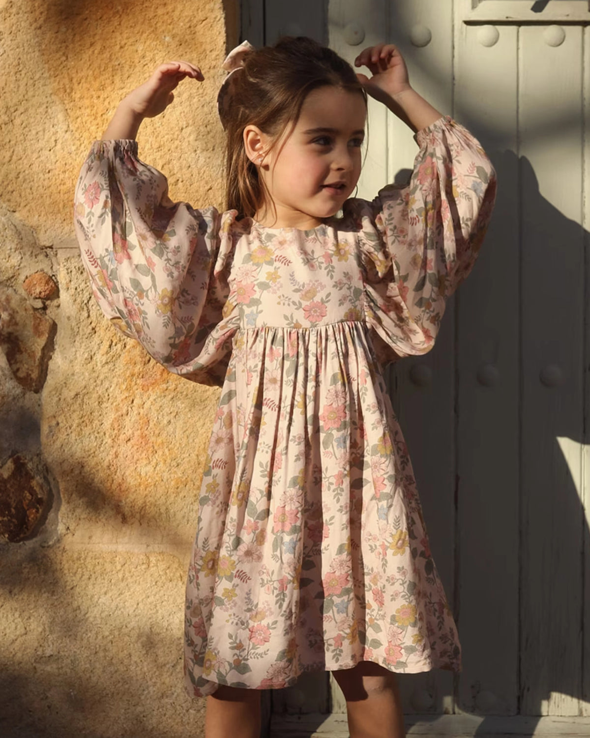 Early Sunday, Belle Dress in Bloom, made from Printed Viscose Twill fabric, featuring a square yoke bodice with puff sleeves and delicate gathered detailing, shown in an angled view of a model wearing outdoors