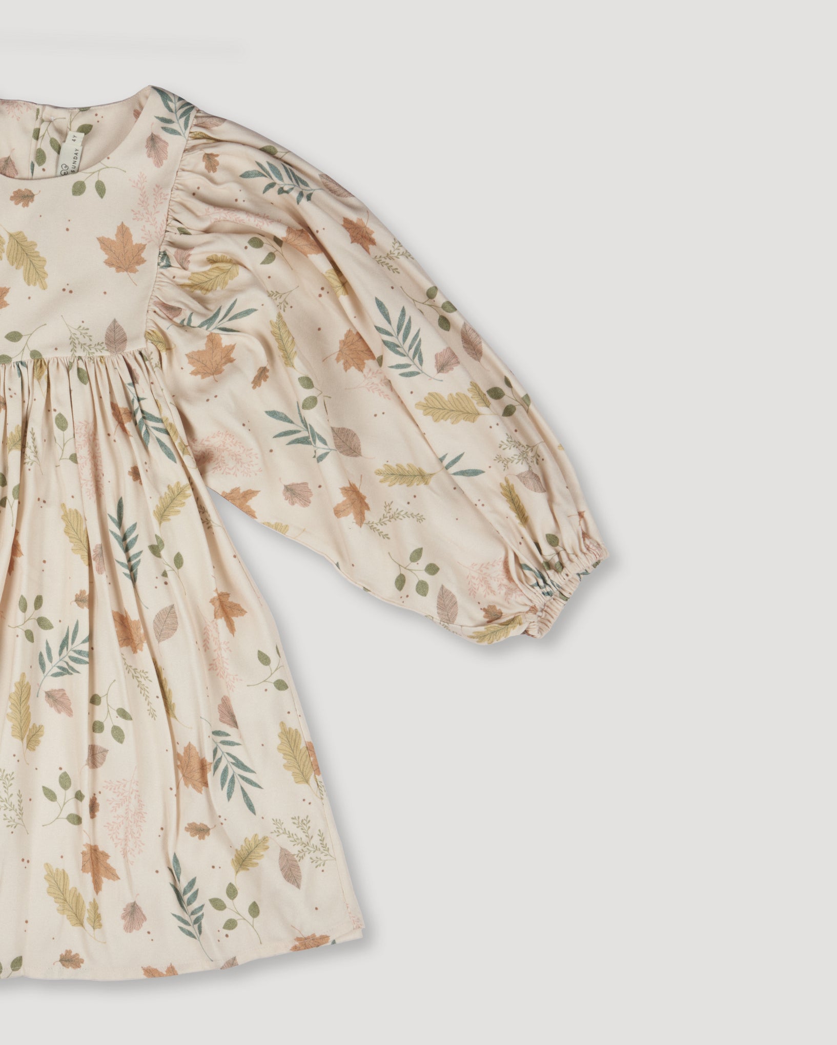 Early Sunday, Belle Dress in Falling Leaves Beige color, made from Printed Viscose Twill fabric, featuring a-line silhouette, bishop sleeves, back button closure, and mid-length, shown in a closeup flat-lay view