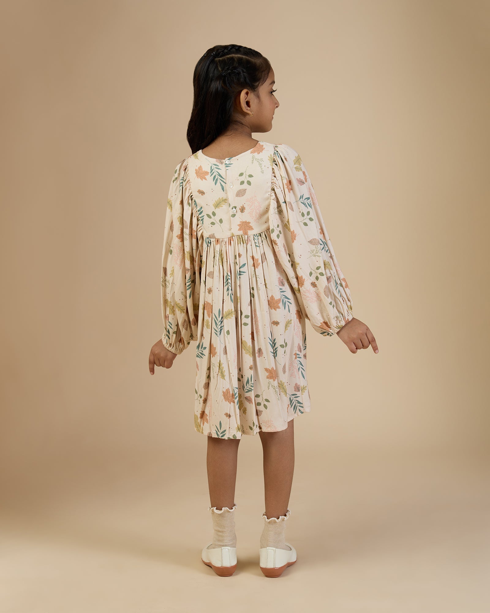 Early Sunday, Belle Dress in Falling Leaves Beige print, made from Printed Viscose Twill fabric, featuring a-line silhouette, bishop sleeves, back button closure, and mid-length, shown in a back view of model wearing it
