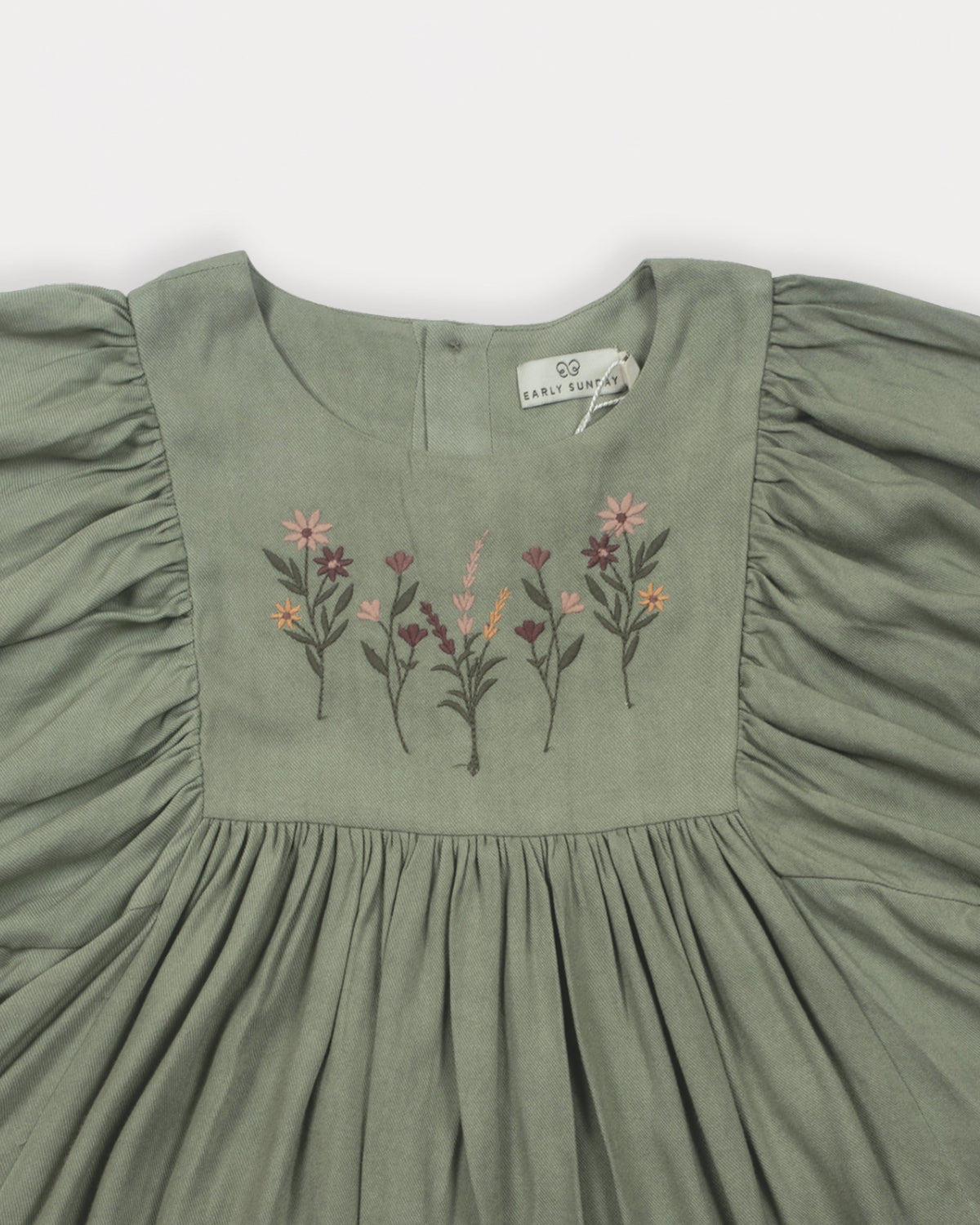 Early Sunday, Belle Dress in Sage Green, made from Viscose Twill fabric, featuring a square yoke bodice with puff sleeves and delicate gathered detailing, shown in a closeup flat-lay view