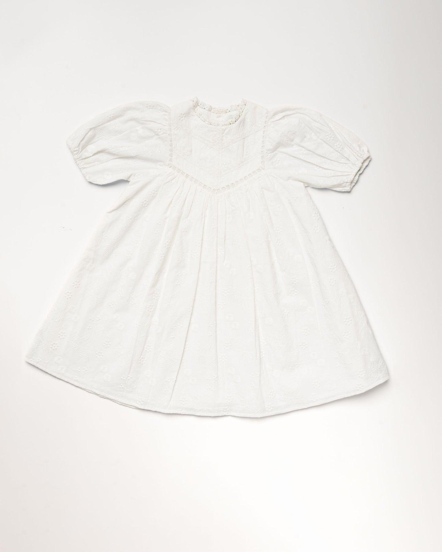 Early Sunday, Beth Dress in Ivory color, made from 100% cotton all over embroidered fabric, featuring Puff sleeves, contrast scalloped collar for a vintage touch, shown in a front flat-lay view.