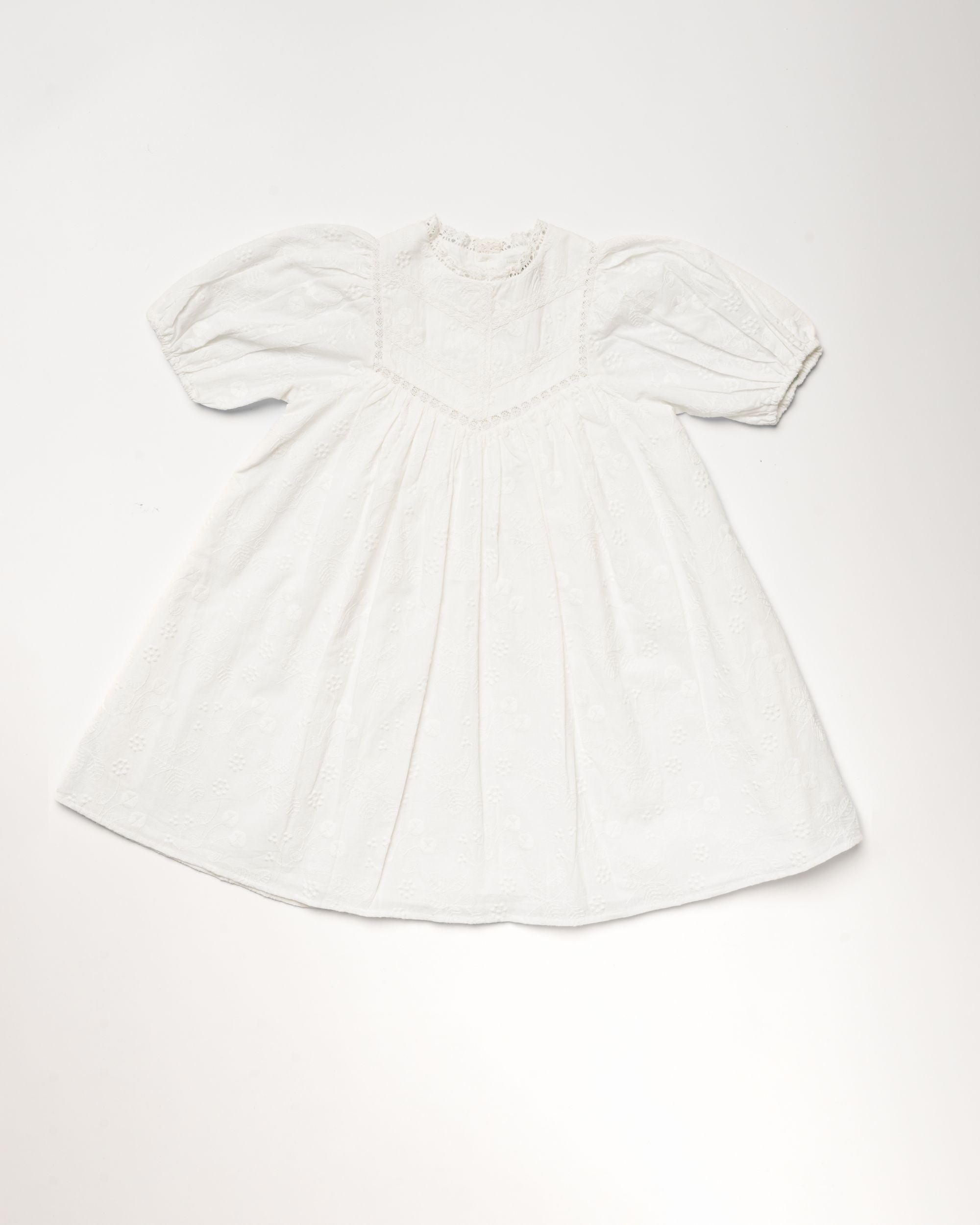 Early Sunday, Beth Dress in Ivory color, made from 100% cotton all over embroidered fabric, featuring Puff sleeves, contrast scalloped collar for a vintage touch, shown in a front flat-lay view.